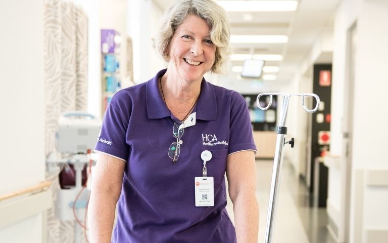 Nurse smiling pushing a wheelchair in a hospital